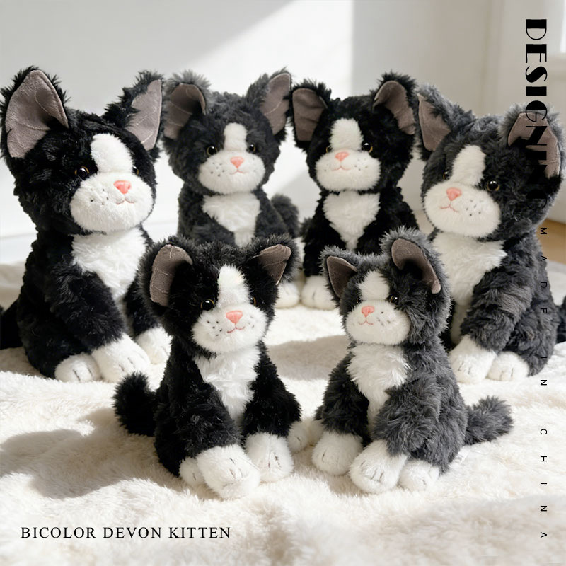 Soft bicolor Devon Rex cat plush toy with big ears and cuddly design, shown in a warm indoor setting with a cozy plush display
