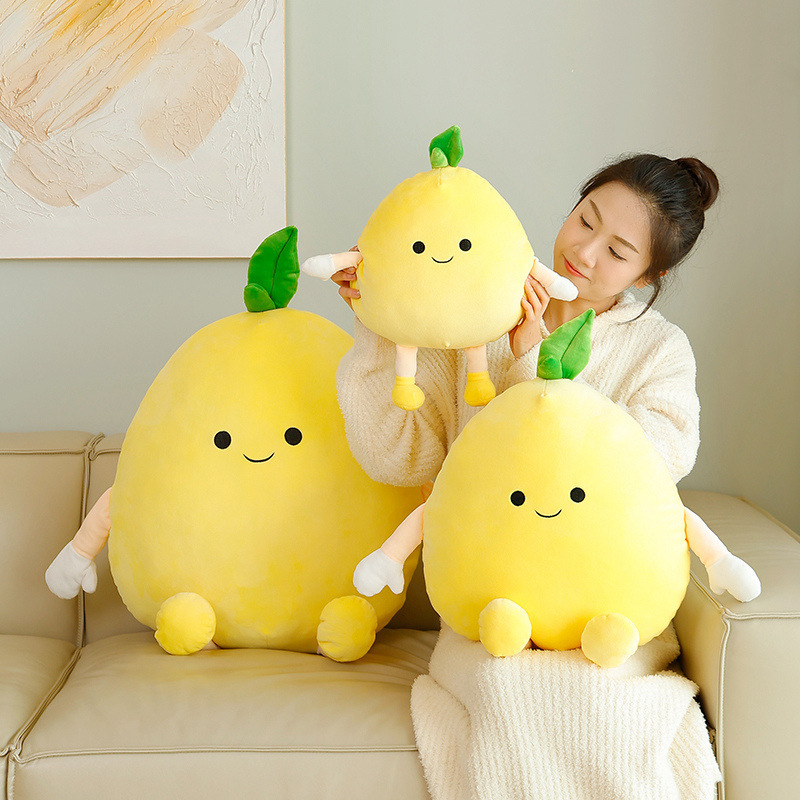 Pomelo plush pillow in soft yellow fabric with cute face and leaf detail, shown on sofa to highlight shape, texture, and cozy home decor styling