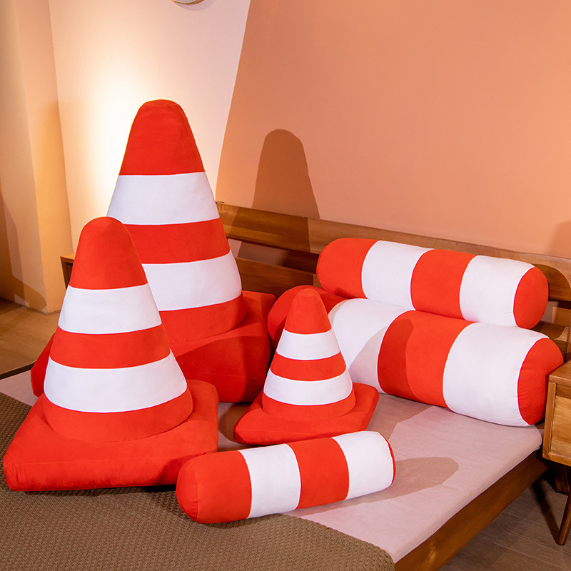 Traffic cone plush pillow and traffic bollard plush pillows in various sizes with orange and white stripes, soft cushions arranged on a bed for display and home decor