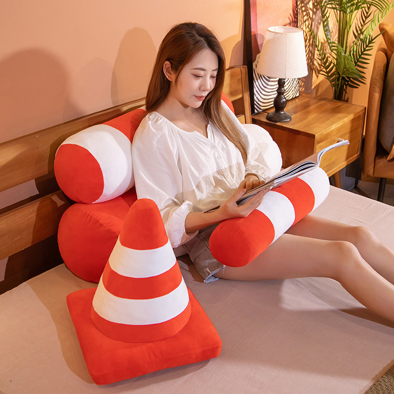 Traffic cone plush pillow and traffic bollard plush cushion with orange and white stripes used on a bed, soft support for reading, lounging, and relaxing