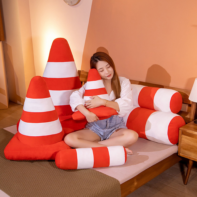 Traffic cone plush pillow in cone shape with orange and white stripes, soft cushion for hugging, lounging, or decorative use on a bed