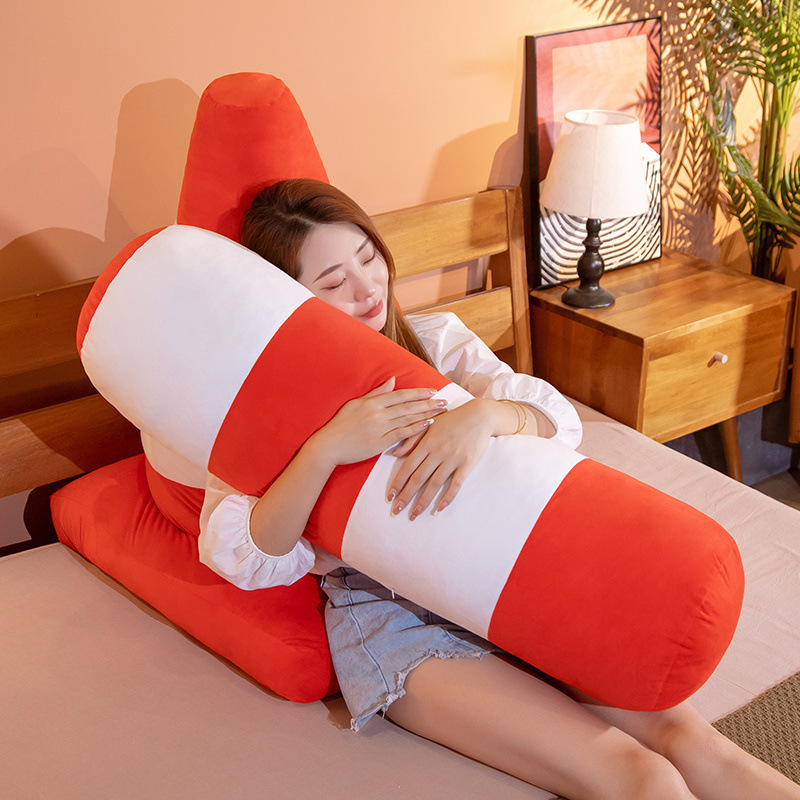 Traffic bollard plush pillow with orange and white stripes used as a soft body cushion on a bed, ideal for hugging, resting, or lounging