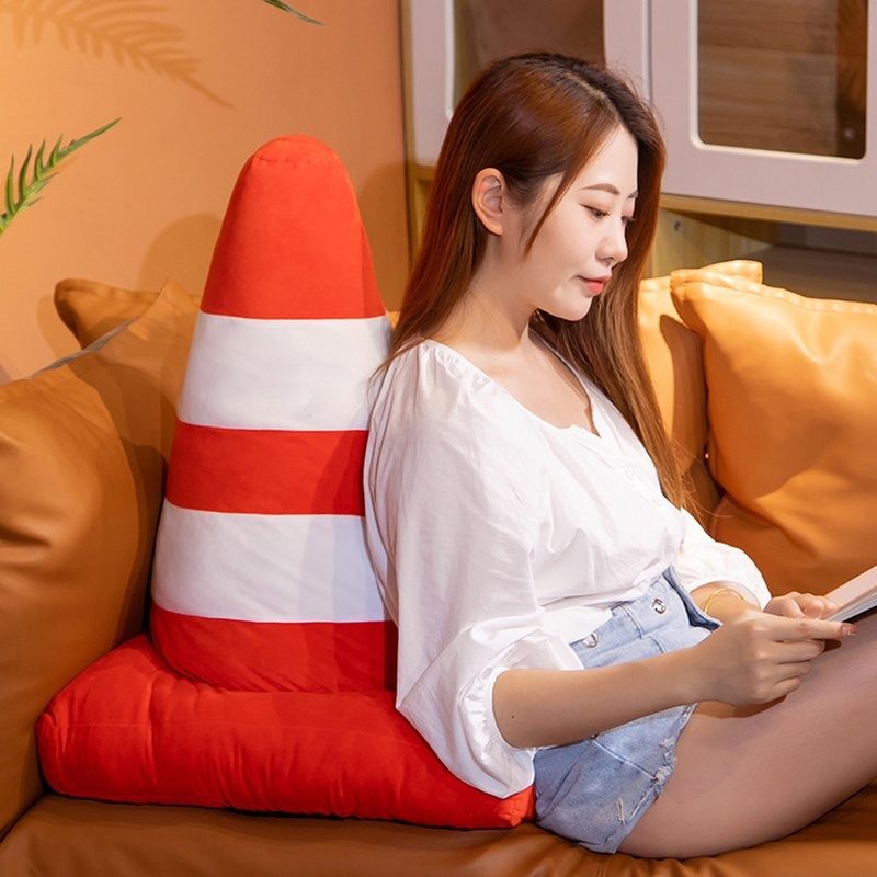 Traffic cone plush pillow in orange and white stripes used as a soft back support cushion, cozy plush design for sitting, relaxing, or reading