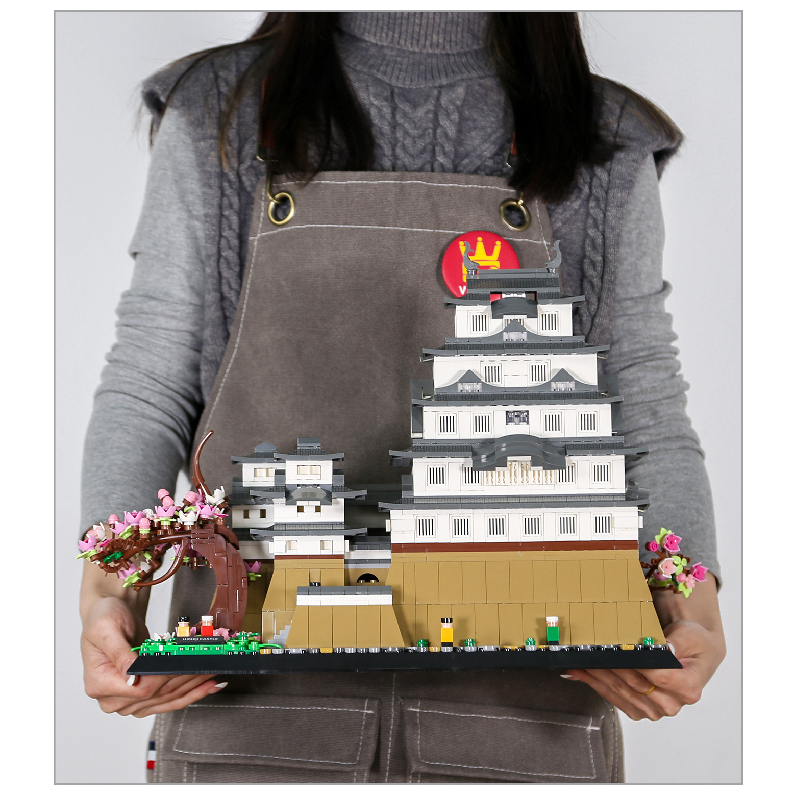 WANGE Himeji Castle building blocks completed model held for scale, showcasing multi-tiered roofs, stone base, and cherry blossom tree details
