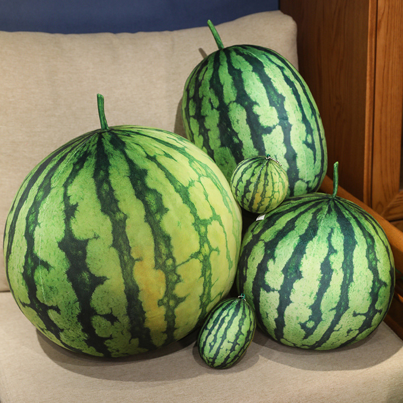 Large realistic watermelon plush pillows and mini keychain cushions displayed on a cozy sofa