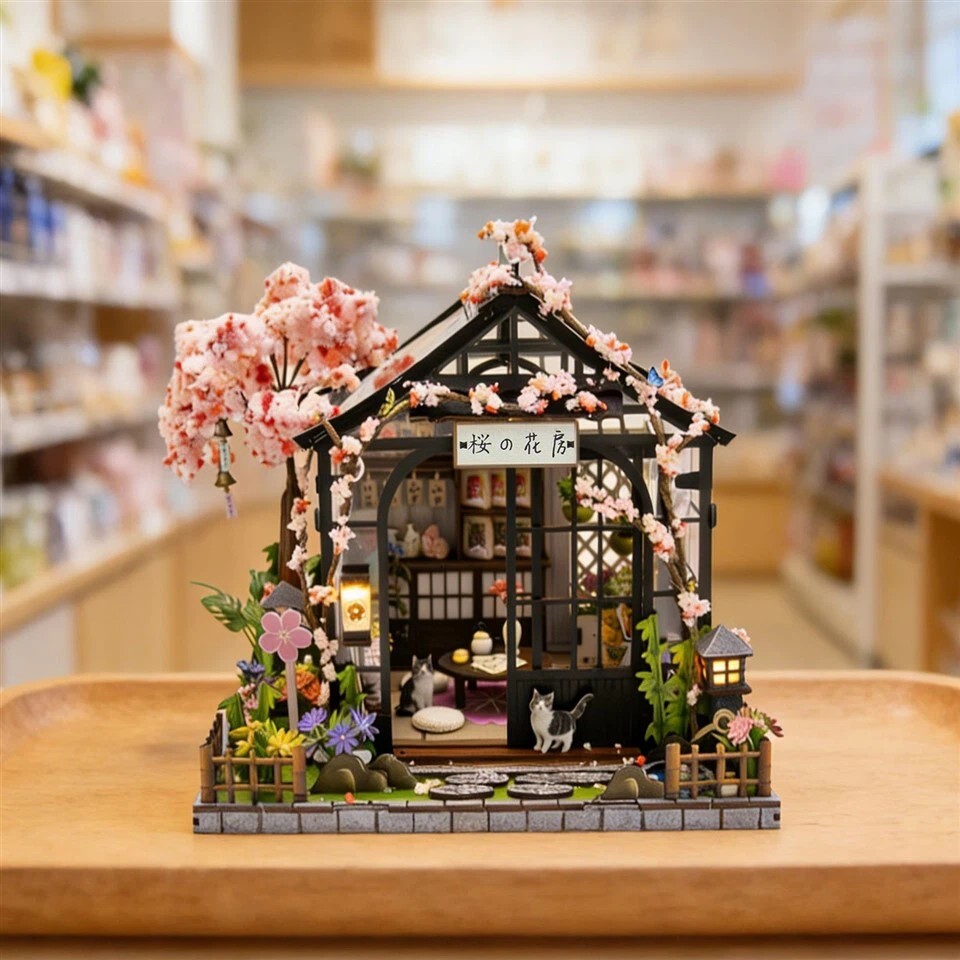 Spring Sakura Greenhouse DIY miniature house displayed on tabletop with cherry blossom decorations, warm lighting, and cozy Japanese-style greenhouse atmosphere
