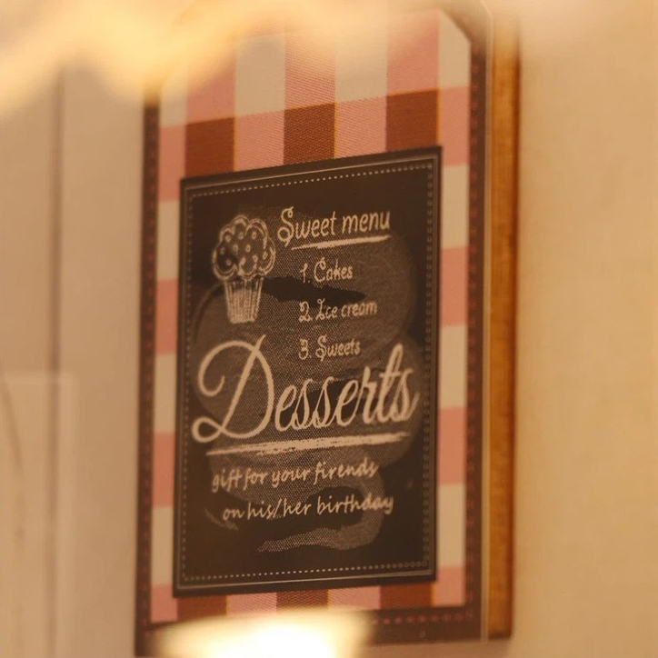 Decorative miniature dessert menu sign with pastel plaid frame and cafe-style typography for a charming handmade chocolate boutique atmosphere