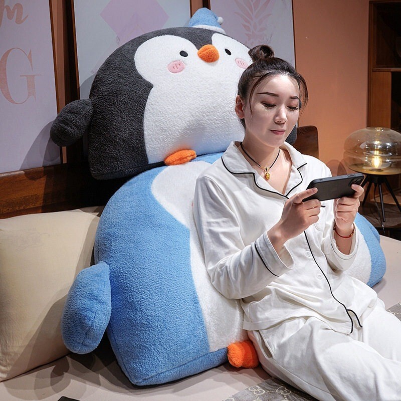 Penguin plush backrest pillow used for comfortable back support while relaxing in bed