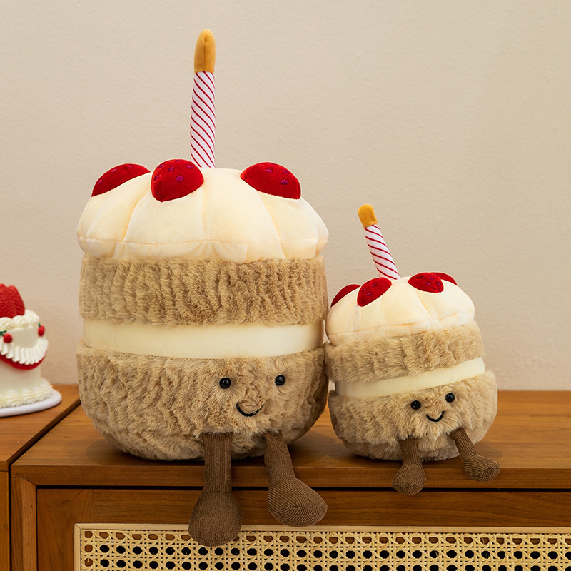 Birthday Cake Plush Toys displayed on a wooden cabinet, showcasing soft plush textures, layered cake details, striped candle accents, and adorable dangling legs