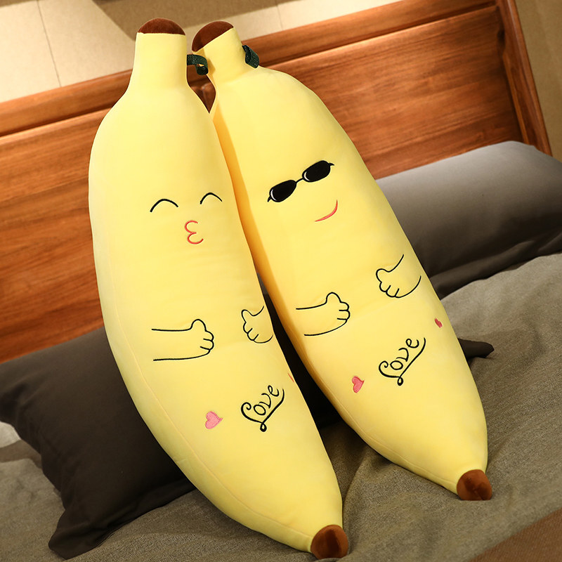 Cute Banana Plush Pillows in Kissing and Sunglasses styles resting on a bed, showcasing playful facial expressions and soft plush construction