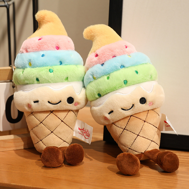 Rainbow Ice Cream Plush Toy with colorful soft serve layers, embroidered winking face, and dangling legs displayed on a tabletop