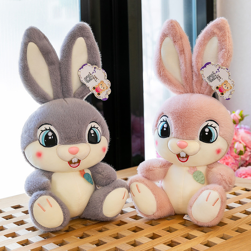 Gray and pink Sweet Bunny plush toys displayed together on a wooden tabletop, showcasing soft plush fabric, embroidered details, and cute bunny expressions in a bright cozy setting
