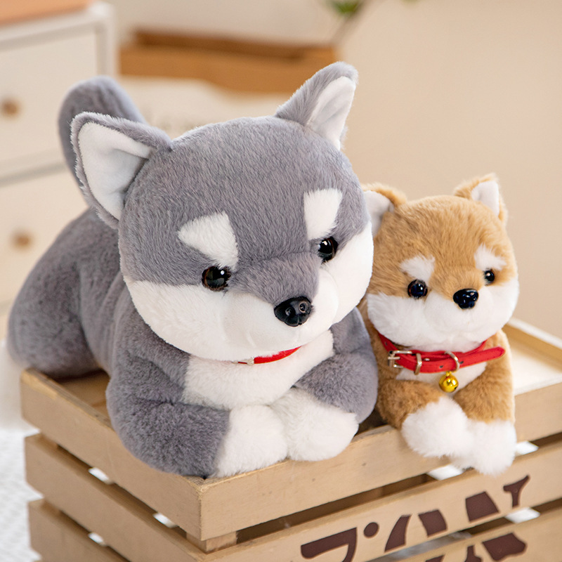Gray and brown Shiba Inu plush toys displayed in a wooden crate, showcasing different sizes in a cozy home setting