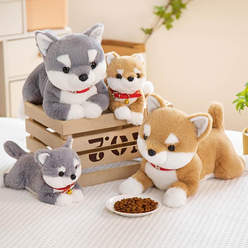 Shiba Inu plush toys in multiple sizes and colors displayed on a bed, creating a warm and playful atmosphere