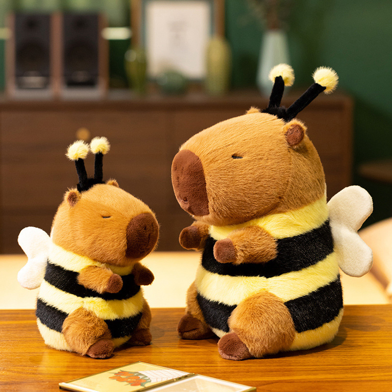 Bee Capybara Plush Toy in 30 cm and 40 cm sizes displayed on a wooden table, featuring fuzzy antennae, soft wings, and black-and-yellow bumblebee stripes in a cozy room setting