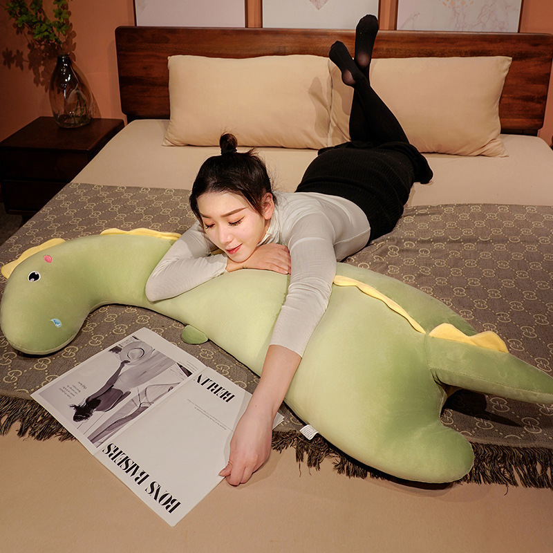 Round Eyes Dinosaur Long Plush Pillow used as a body pillow while lounging on a bed, providing soft support for reading and relaxation