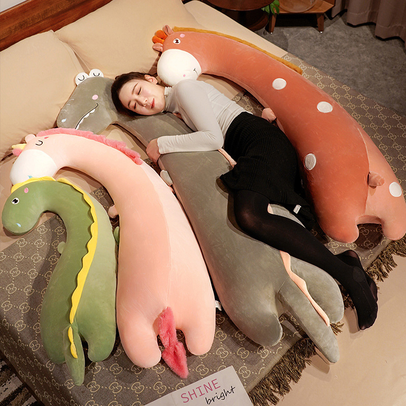 Giraffe, unicorn, and dinosaur long plush pillows displayed on a bed, showcasing their curved body pillow design for hugging, sleeping, lounging, and cozy relaxation