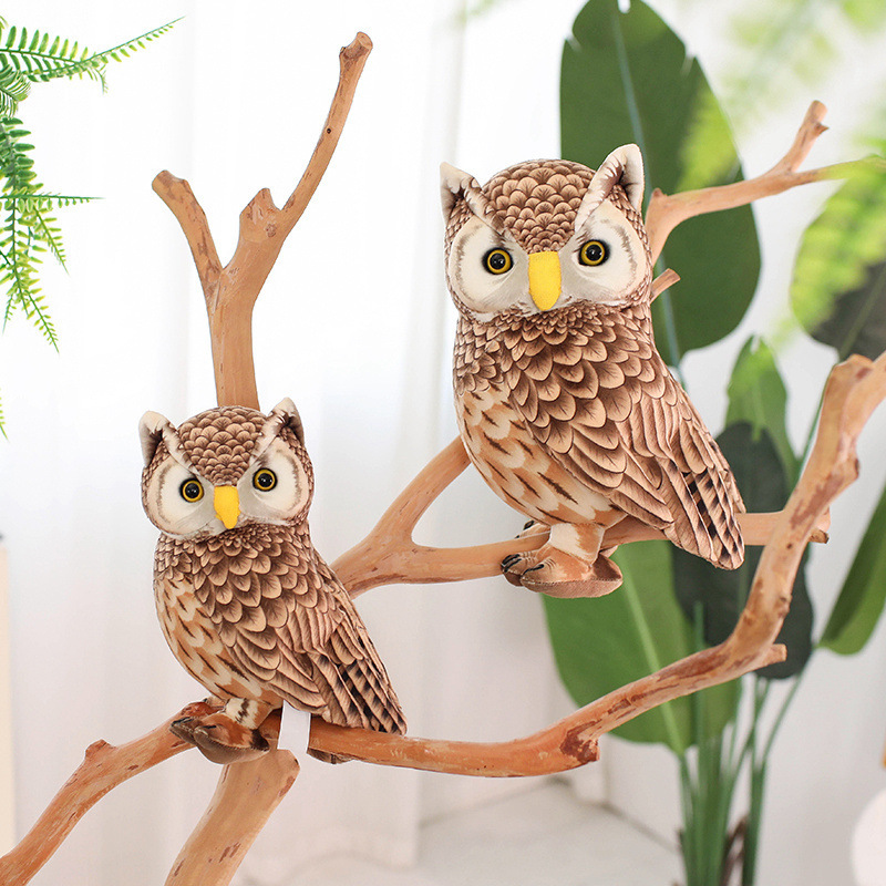 Cute Owl Plush Toy displayed on decorative tree branches, featuring detailed feather-inspired printing and bright expressive eyes in a woodland-inspired setting