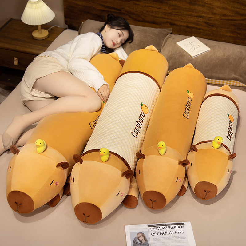 Cute Capybara Long Plush Pillows in plush and cooling fabric styles displayed on a bed, featuring a sleepy capybara design with a tiny duck companion and multiple size options