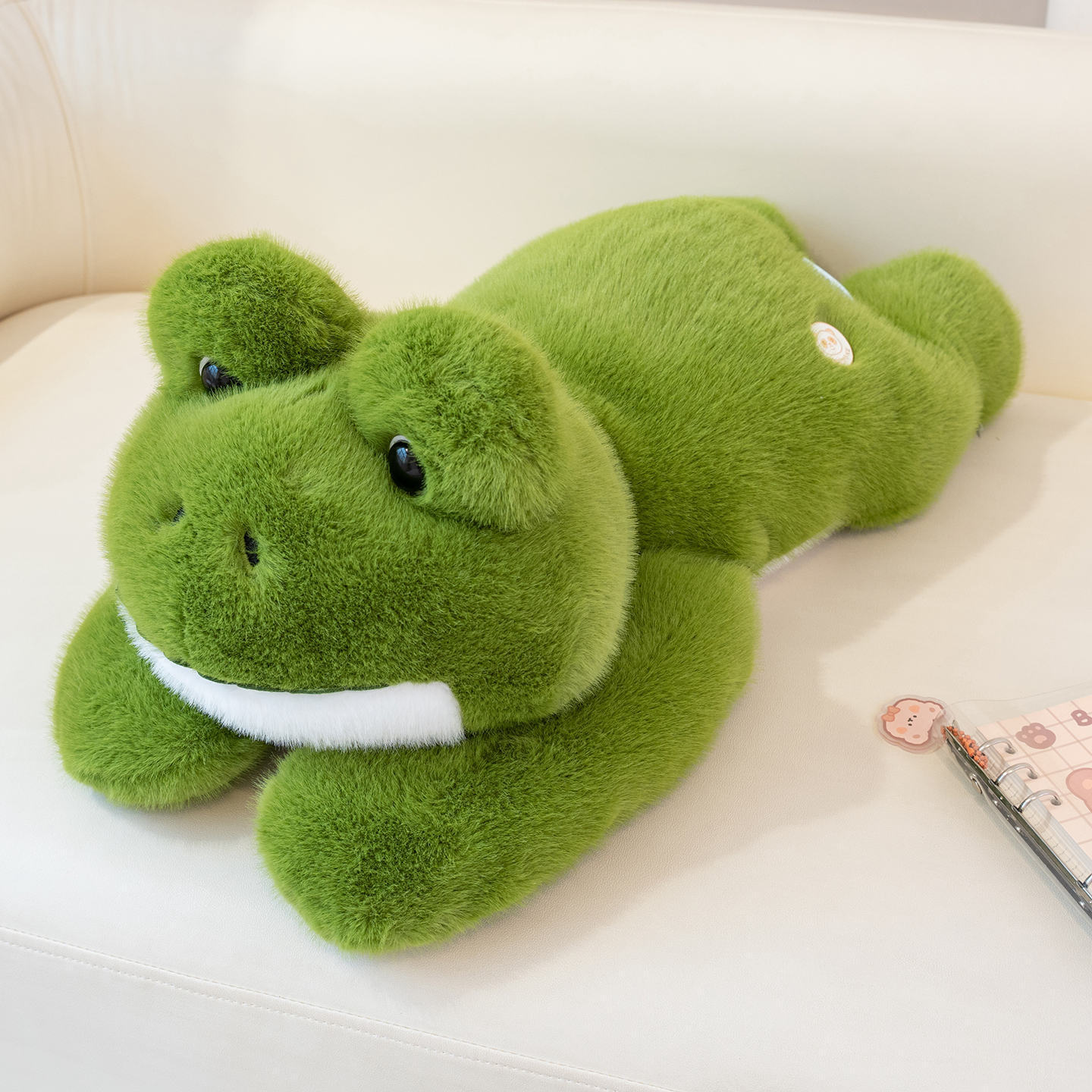 Cute Frog Plush Toy displayed on a sofa, showcasing its fluffy texture and adorable frog-shaped design