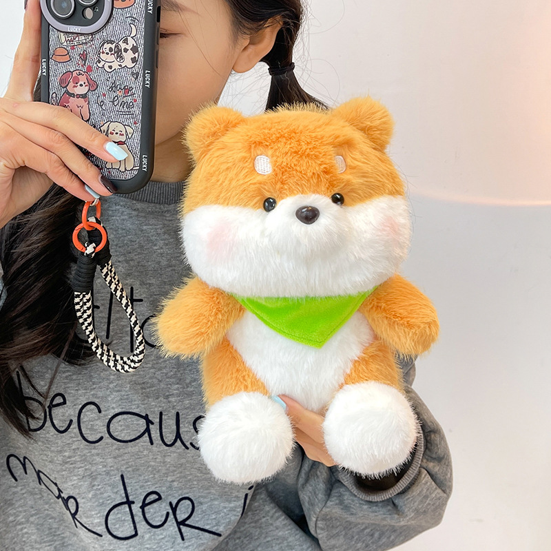 Small Shiba Inu plush toy with a green bandana showcasing fluffy cheeks, soft texture, and embroidered facial details