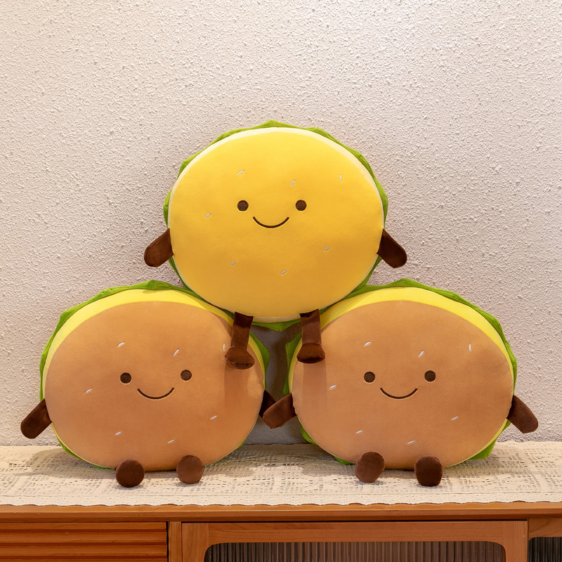 Cute burger plush pillows in yellow and brown color options displayed together, featuring smiling faces, soft plush fabric, and playful food-themed home decor