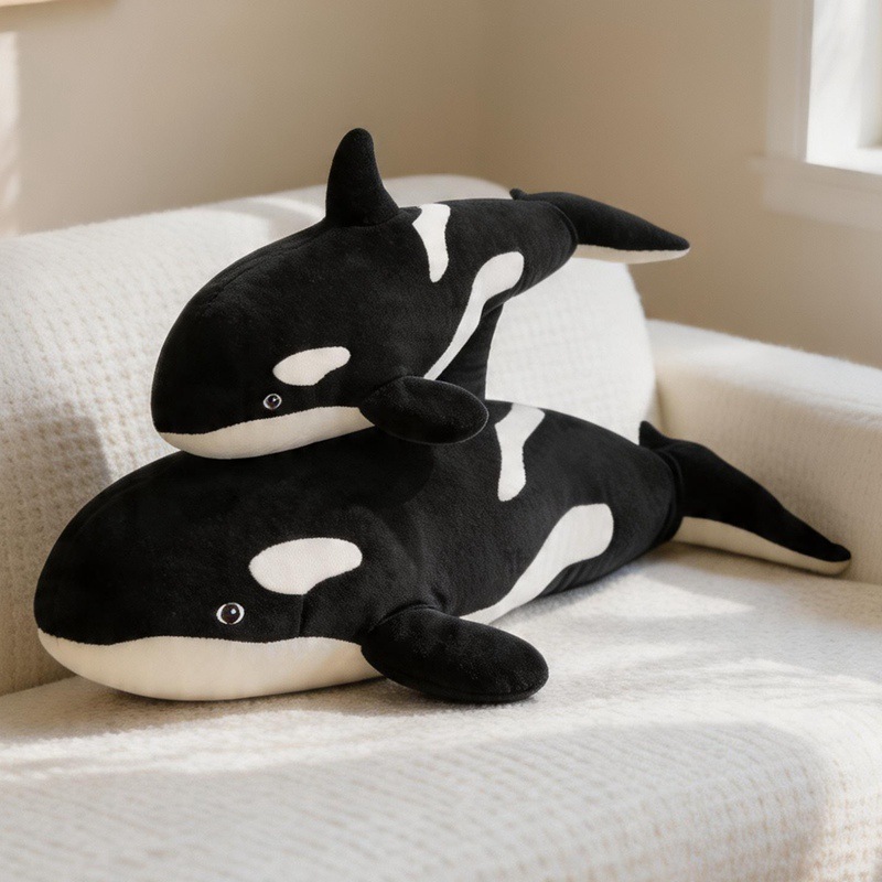Orca Killer Whale plush pillows displayed on a sofa, showcasing soft plush fabric and cuddly whale designs in multiple sizes