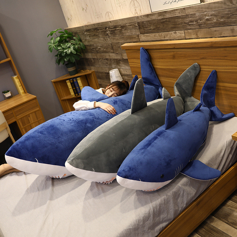 Megalodon Shark Plush Toy on a bed, featuring a long huggable design for relaxing and cozy comfort