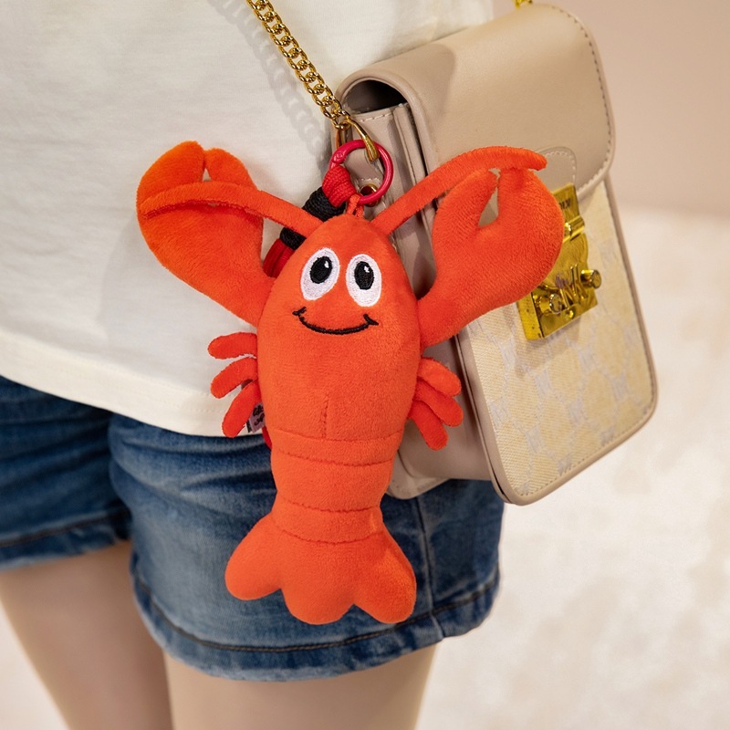 18 cm Cute Lobster Plush Keychain attached to a shoulder bag, featuring a smiling lobster design, soft plush fabric, and oversized claws for a playful everyday accessory
