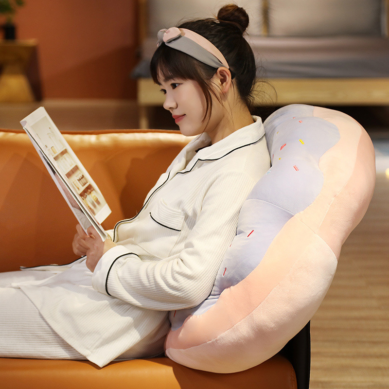 Sweet Donut Plush Pillow used as comfortable back support while reading in a cozy home setting