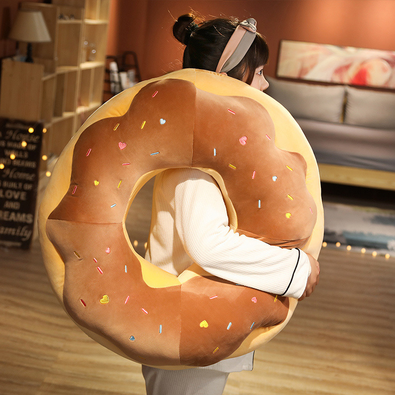 Chocolate Donut Plush Pillow with soft plush fabric and colorful embroidered sprinkles shown in a cozy home setting