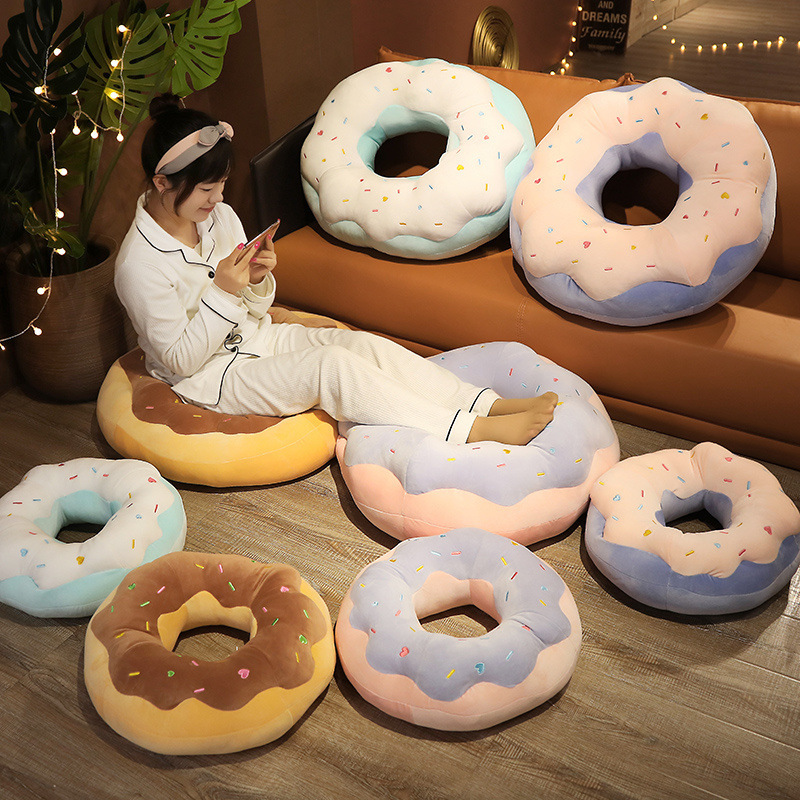 Donut Plush Pillows in raspberry, taro, sea salt, and chocolate designs arranged in a cozy living space