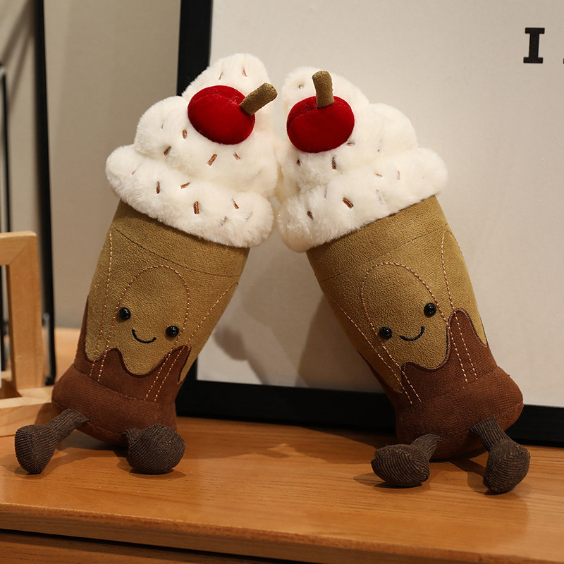 Chocolate milkshake plush toys displayed together with smiling faces, fluffy whipped cream, cherry topping, and dangling legs for cute desk or shelf decor