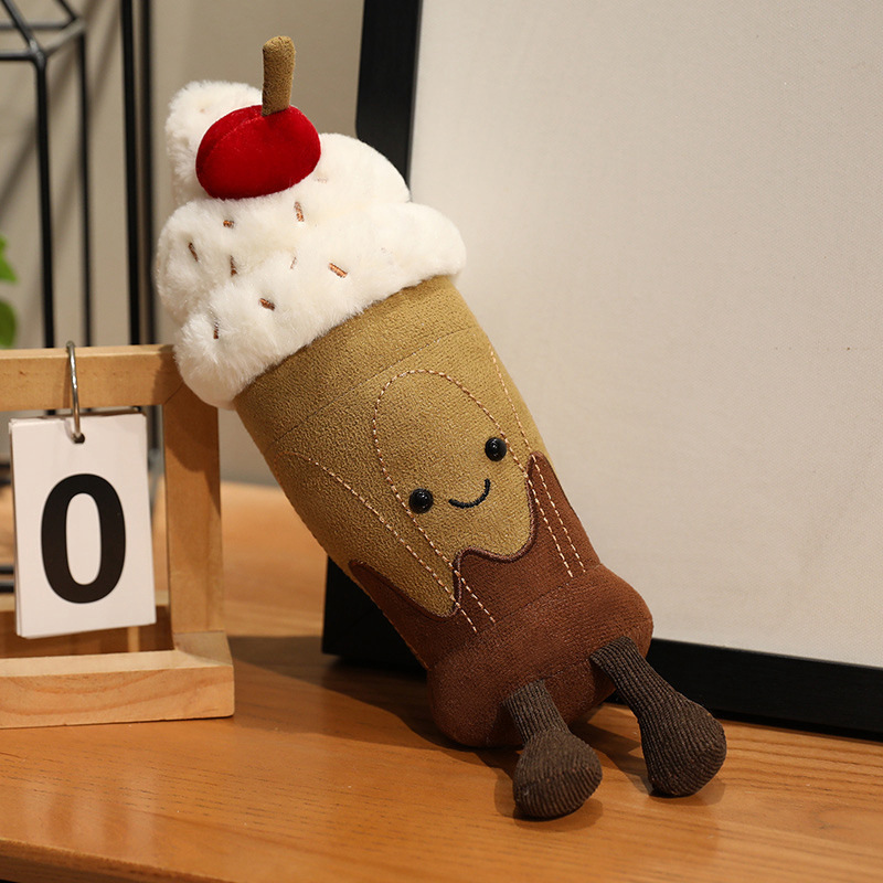 Cute Chocolate Milkshake Plush Toy leaning on a tabletop, featuring soft plush fabric, fluffy whipped cream, cherry topping, and dangling legs