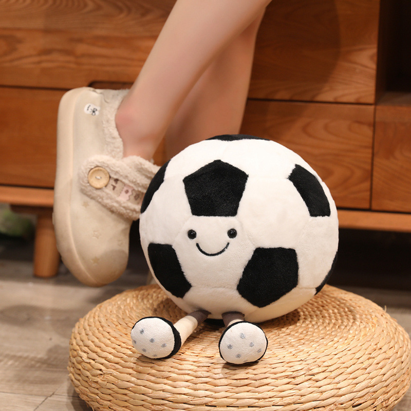 Soccer Ball Plush Toy with smiling face and dangling legs displayed on a woven floor cushion for cozy home decor