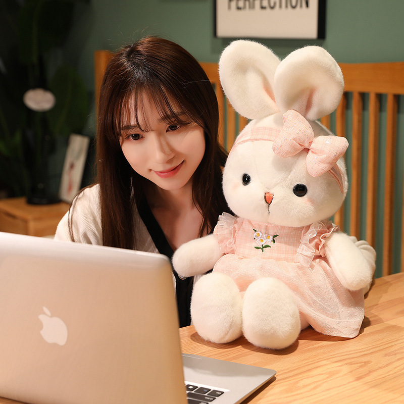 Pink Cute Bunny Plush Toy with a daisy embroidered dress and matching bow headband displayed beside a laptop, adding a cozy touch to desks, bedrooms, and workspaces