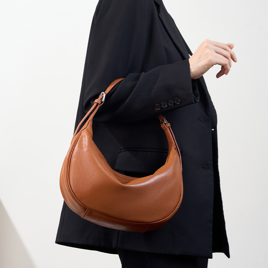 Model carrying Luna Leather Hobo Bag in Caramel – top handle style