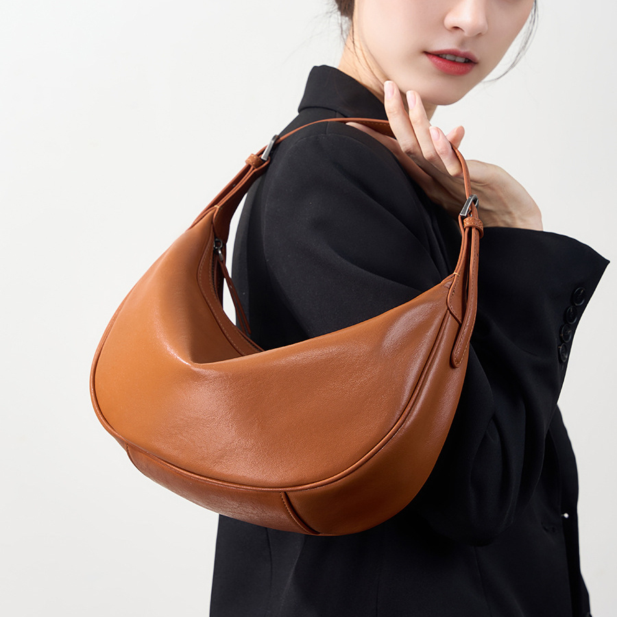 Model carrying Luna Leather Hobo Bag in Caramel – top handle style