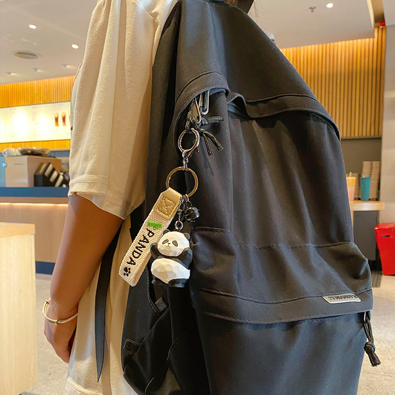 Waving panda keychain charm hanging on a bag