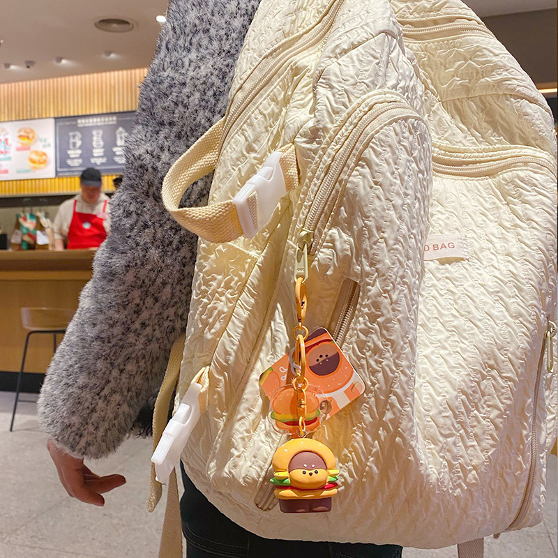 Burger dog keychain charm hanging on a bag