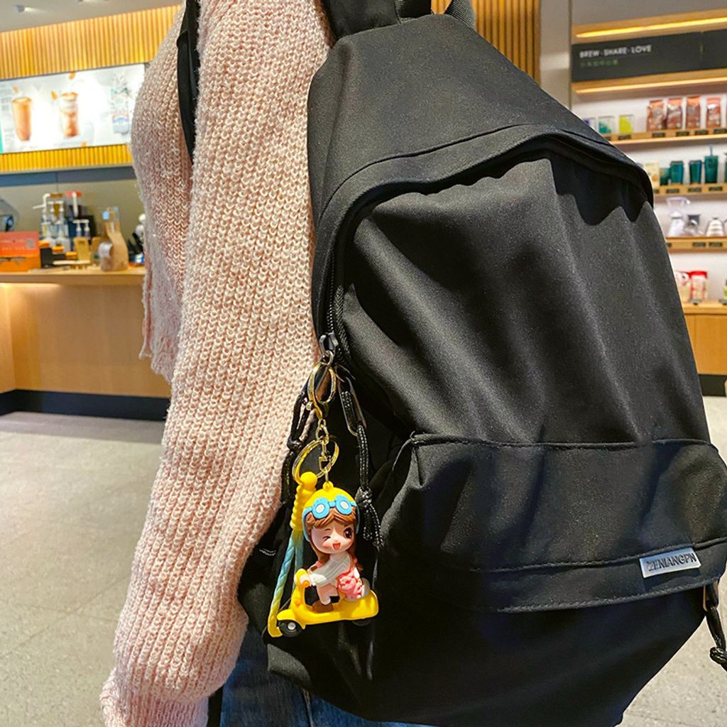 Electric scooter girl keychain charm in yellow hanging on a bag