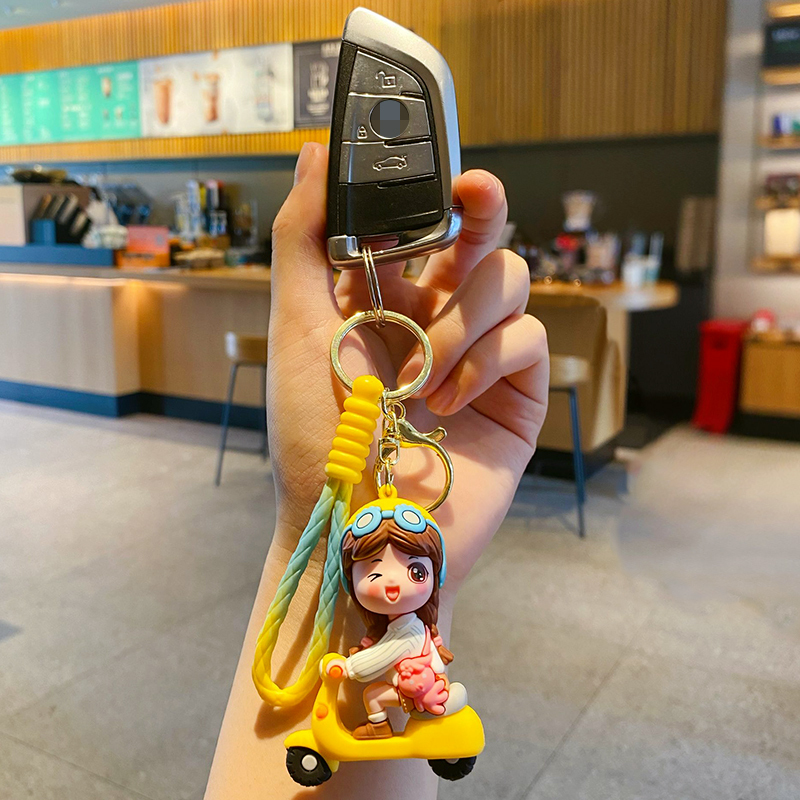 Electric scooter girl keychain charm in yellow attached to a car key fob