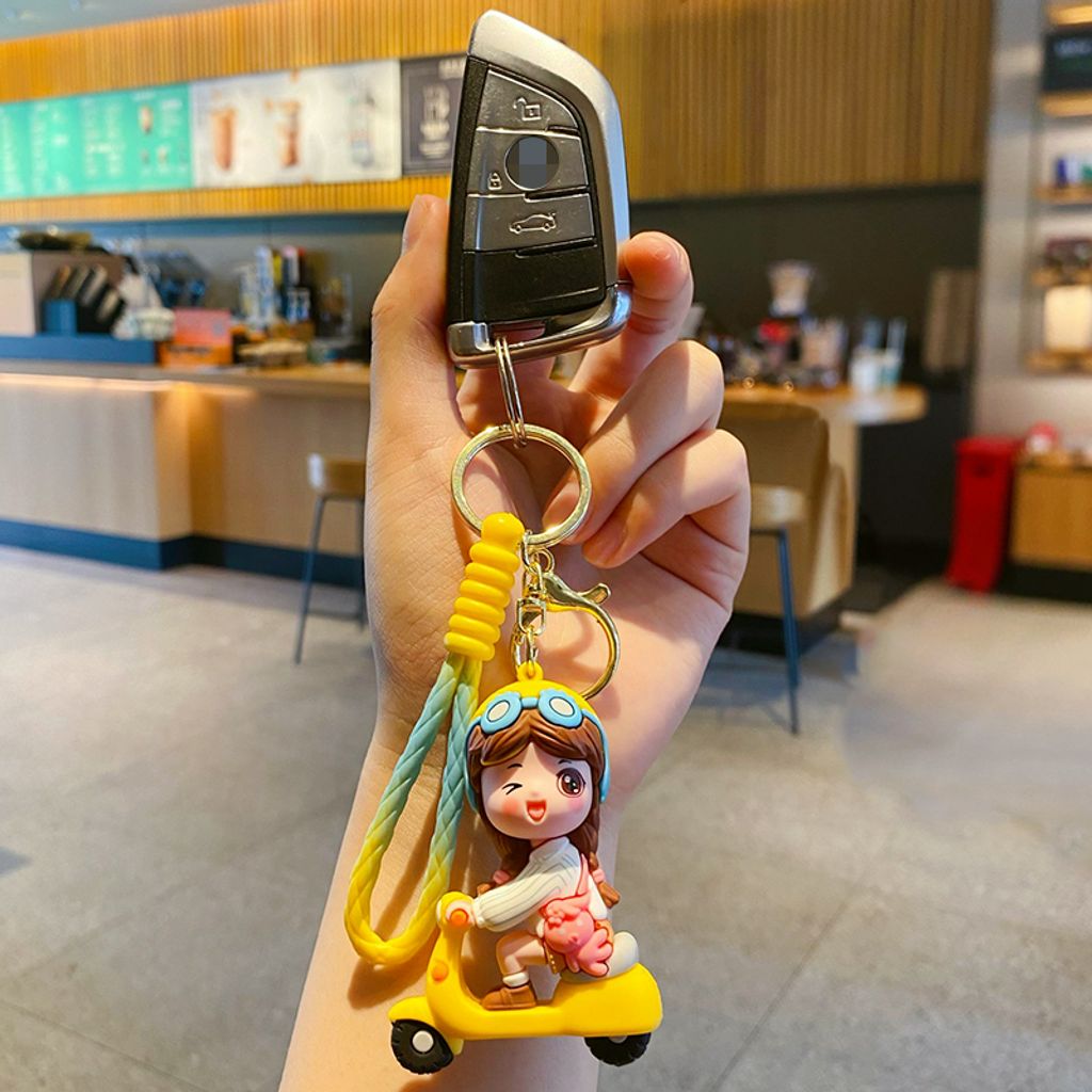 Electric scooter girl keychain charm in yellow attached to a car key fob