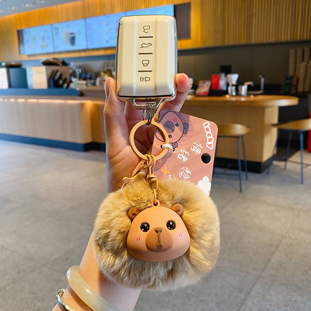 Capybara pom pom keychain charm attached to a car key fob