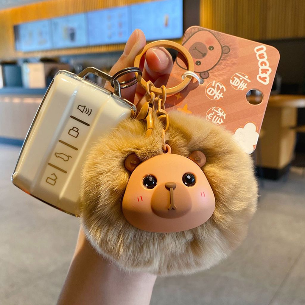 Capybara pom pom keychain charm attached to a car key fob