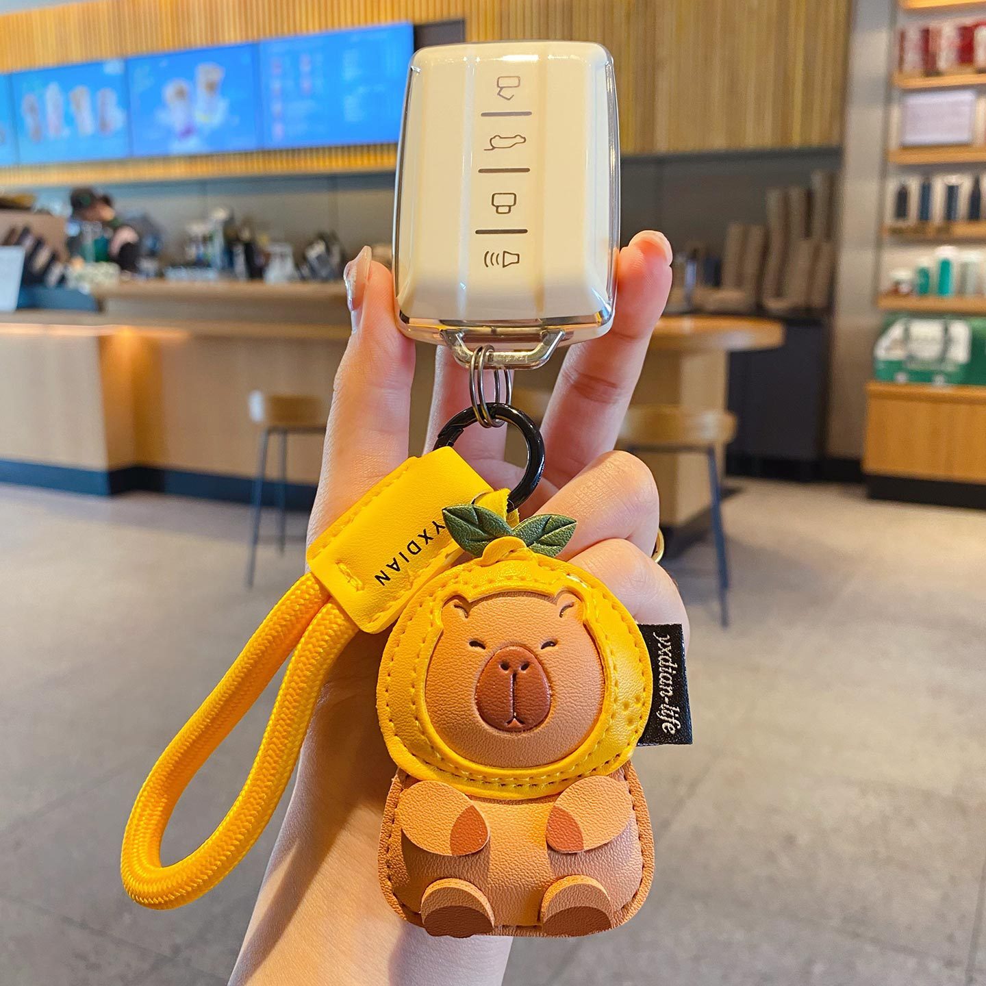 Cute leather capybara keychain charm attached to a car key fob