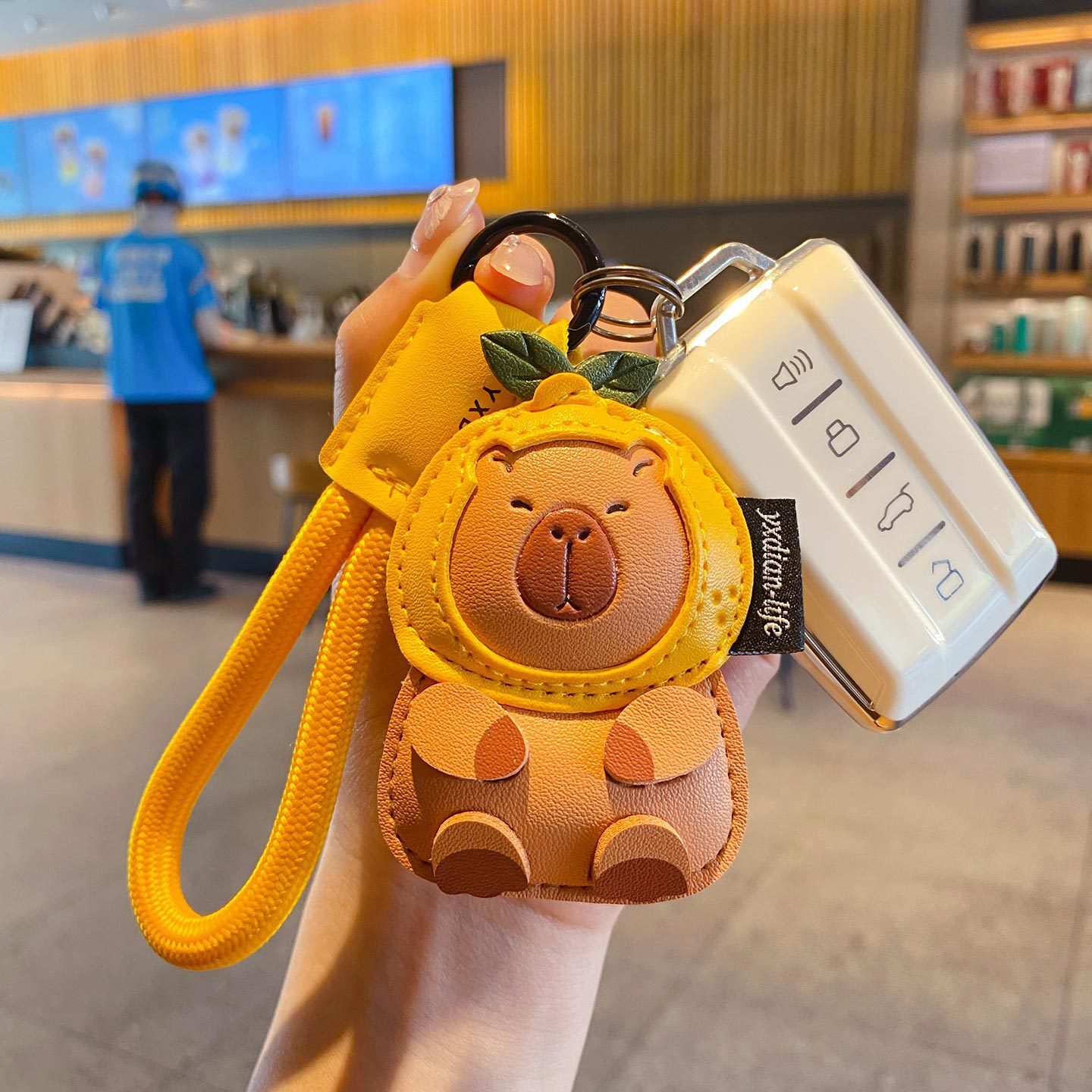 Cute leather capybara keychain charm attached to a car key fob