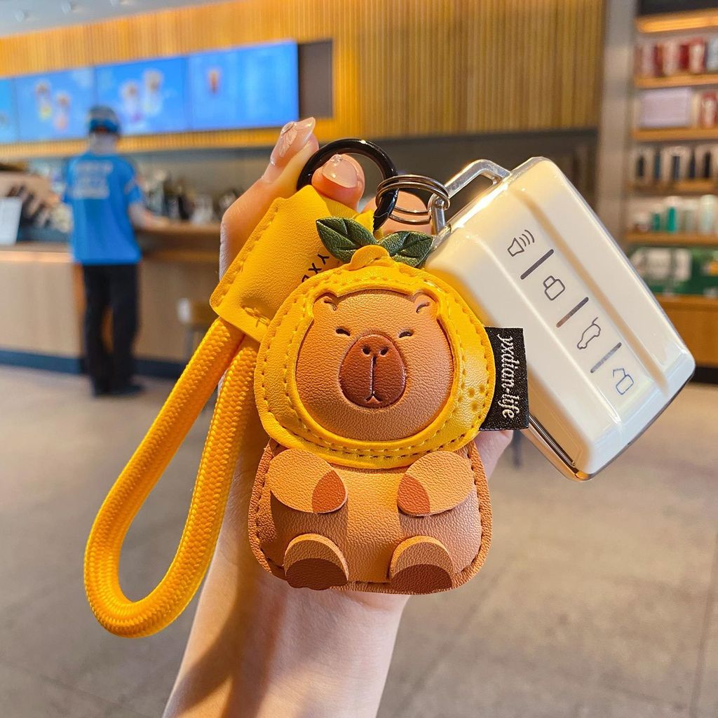 Cute leather capybara keychain charm attached to a car key fob