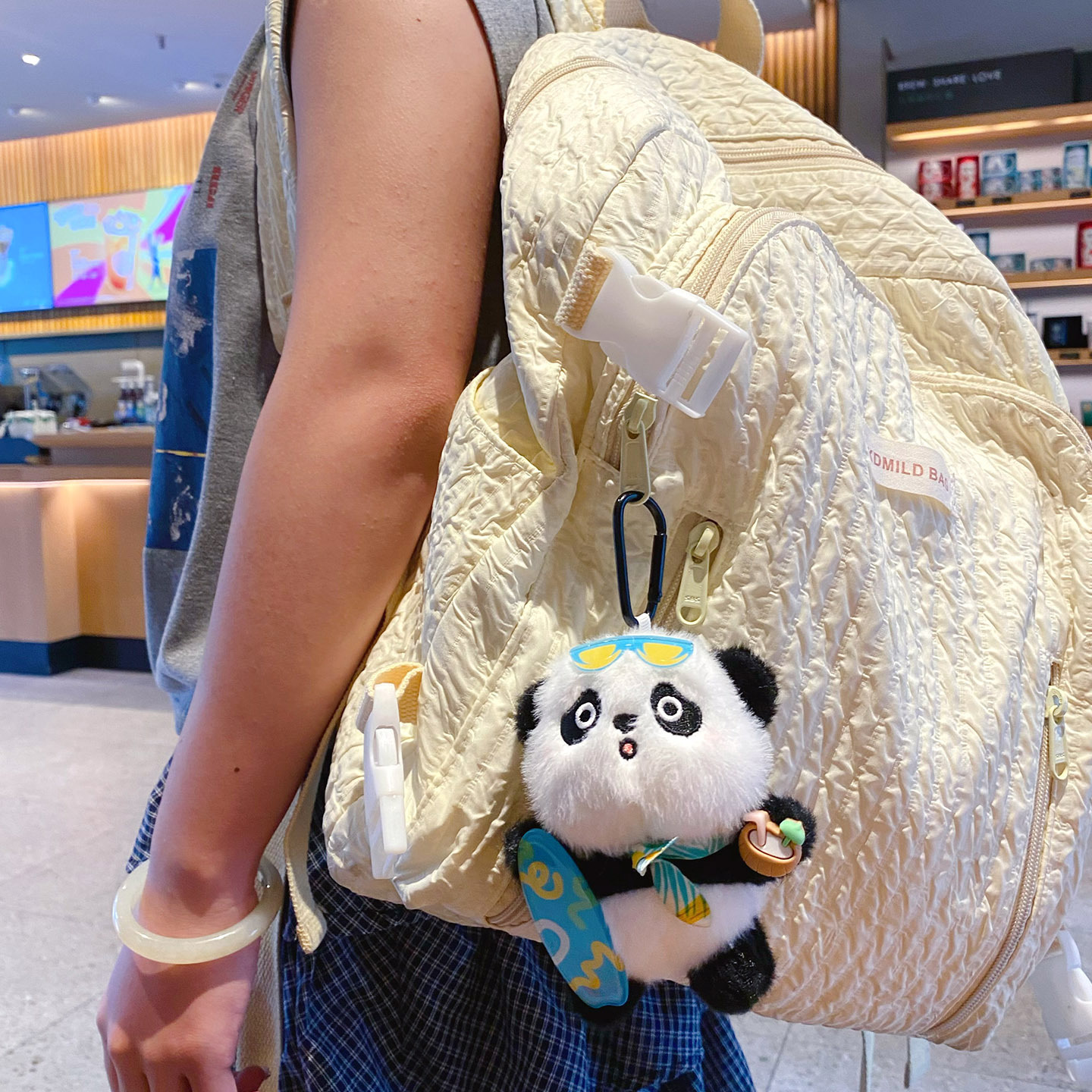 Panda plush skateboard keychain charm hanging on a bag