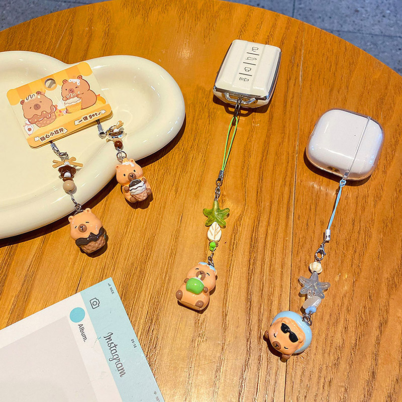 Dessert capybara keychain charm pair and beach capybara beaded charms attached to a car key fob and an earphone case
